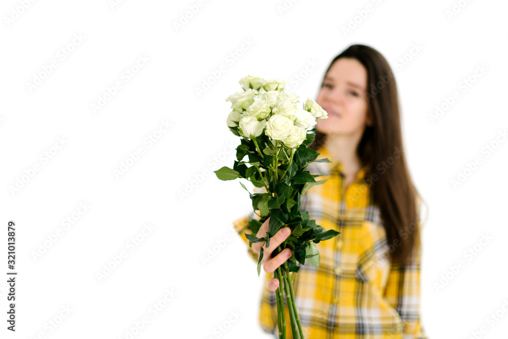 Beautiful brunette woman in a yellow shirt on a white background in the hands of white flowers. The concept of spring and happiness Beautiful brunette woman in a yellow shirt on a white background in the hands of white flowers. The concept of spring and happiness