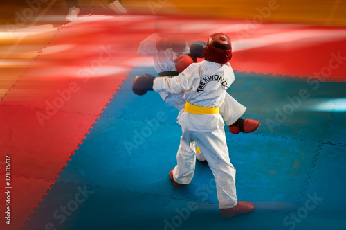 Martial Arts - Taekwondo. Kids in traditional kimano, hard hats and gloves. Sports duel. For atmospheric, a motion blur film noise effect has been added. Text: Taekwondo is the name for martial art.