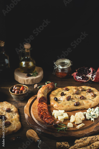 Mediterranean style appetizer with focaccia and olives on dark wooden rustic background