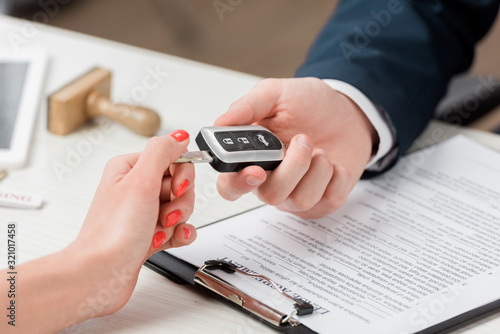 cropped view of realtor giving key to woman, leasing concept