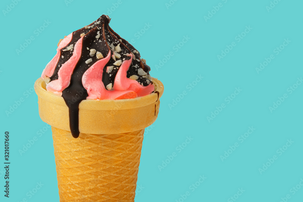 Ice cream. Sweet pink ice cream in a waffle cone poured with chocolate on a turquoise background.Beautiful dessert.