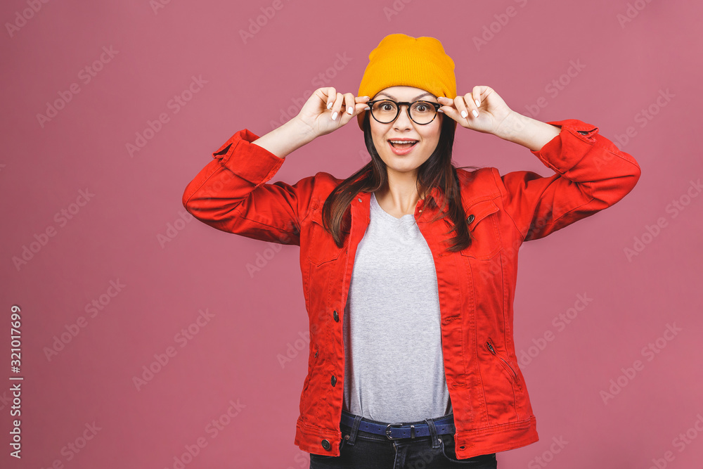 Having fun! Portrait of happy young hipster woman in yellow hat and red shirt isolated over pink background. Having fun! Portrait of happy young hipster woman in yellow hat and red shirt isolated over pink background.