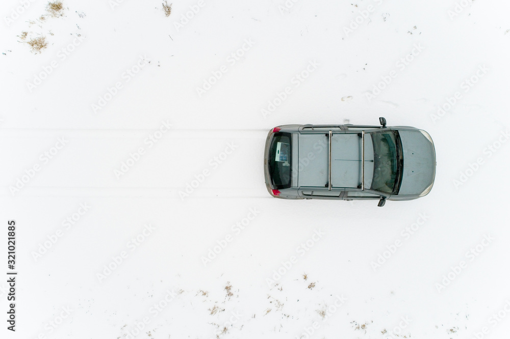 Top view on a car that stands in a snow-covered field. Nearby are human footprints.