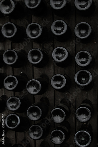 The bottom of the wine bottles is displayed on shelves in the open air. Creative dark and textured abstract background. Alcohol concept.