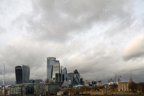 City of London in the UK. View over the River Thames to the city of London and the Tower of London with dramatic stormy clouds. Cityscape of the business district and Tower of London in 2020.