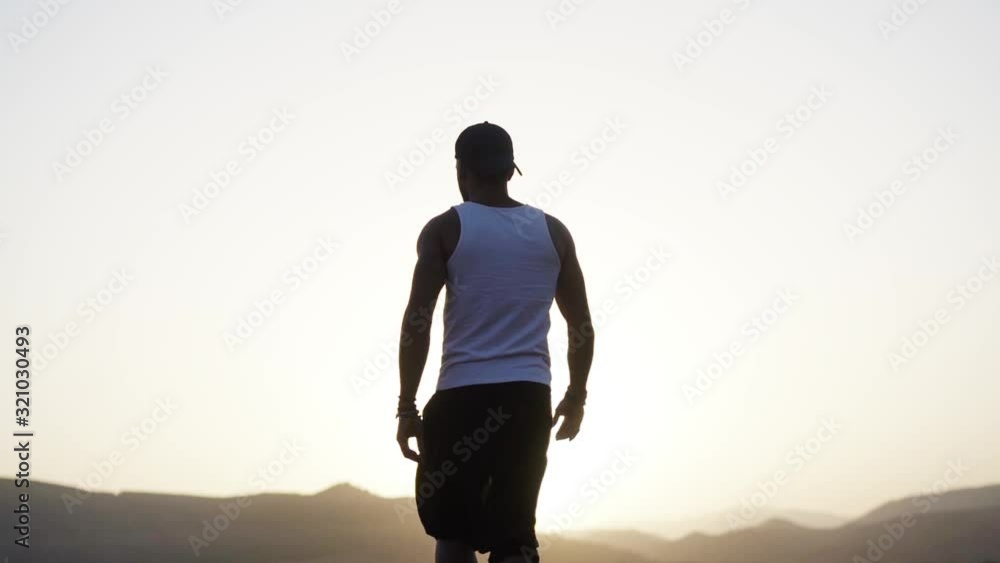 man walking towards the edge of a cliff at sunrise man walking towards the edge of a cliff at sunrise