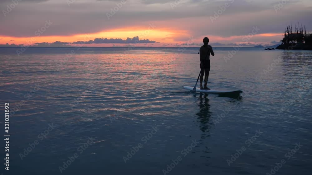 Silhouette of man paddle boarding at sunset Silhouette of man paddle boarding at sunset