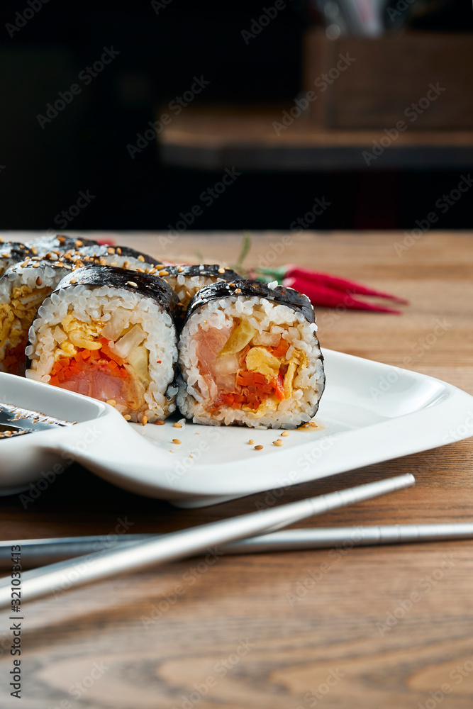 Korean traditional rolls - Gimbap with boiled rice and other ingridients on a white plate on a wooden background. Selective focus. Tasty street food Korean traditional rolls - Gimbap with boiled rice and other ingridients on a white plate on a wooden background. Selective focus. Tasty street food
