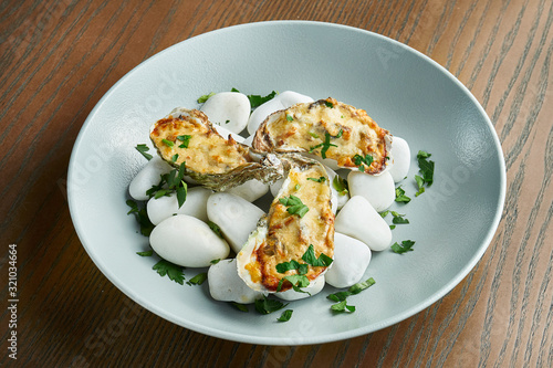 Baked oysters with cheese on the sea, hot stones on a wooden background. Healthy seafood. Film effect during post. Soft focus