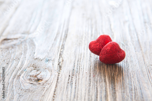 Two red heart on wooden table textured against bokeh background