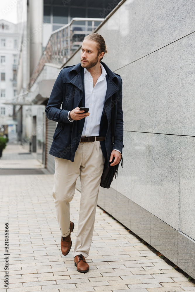 Attractive young bearded businessman walking outdoors