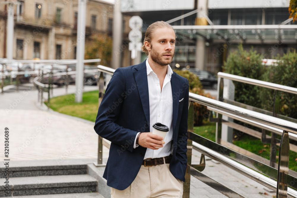 Attractive young bearded businessman walking outdoors Attractive young bearded businessman walking outdoors