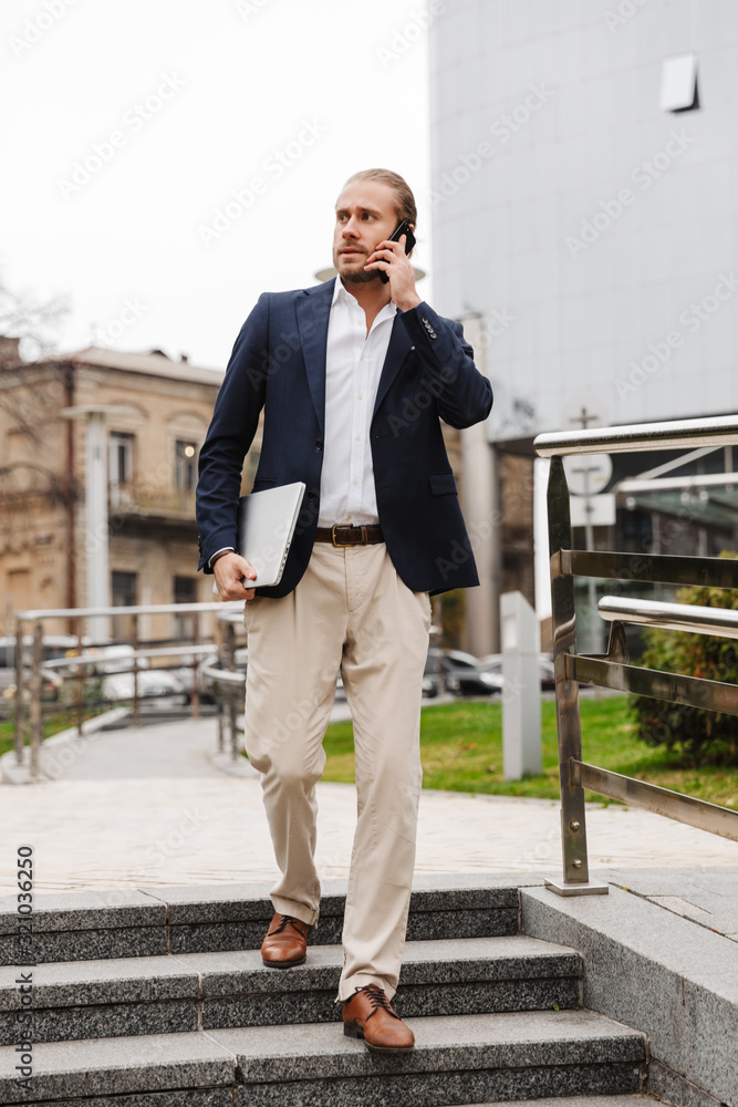 Attractive young bearded businessman walking outdoors Attractive young bearded businessman walking outdoors