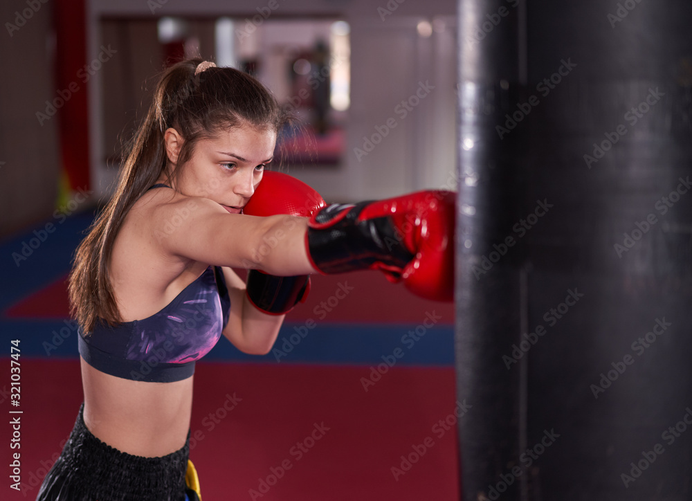 Young boxer girl hitting the heavy bag