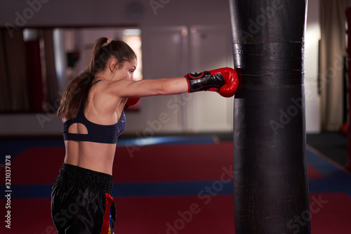 Young boxer girl hitting the heavy bag