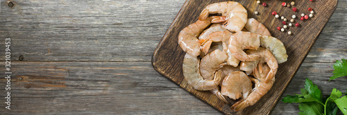 Tiger prawns on a wooden Board on a gray wooden table. Banner