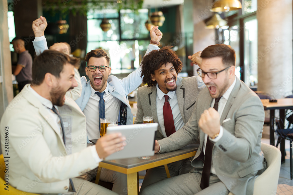 Happy creative business colleagues having a drink after work and using tablet. The beginning of the weekend. Successful working week Happy creative business colleagues having a drink after work and using tablet. The beginning of the weekend. Successful working week
