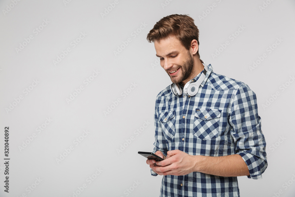 Portrait of smiling young man with headphones using cellphone