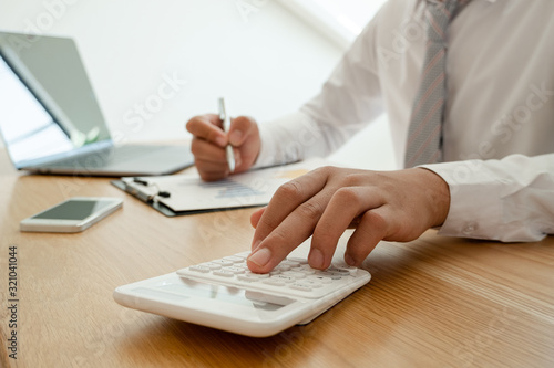 A business man is sitting at a desk and calculating financial graphs about real estate investment expenditures