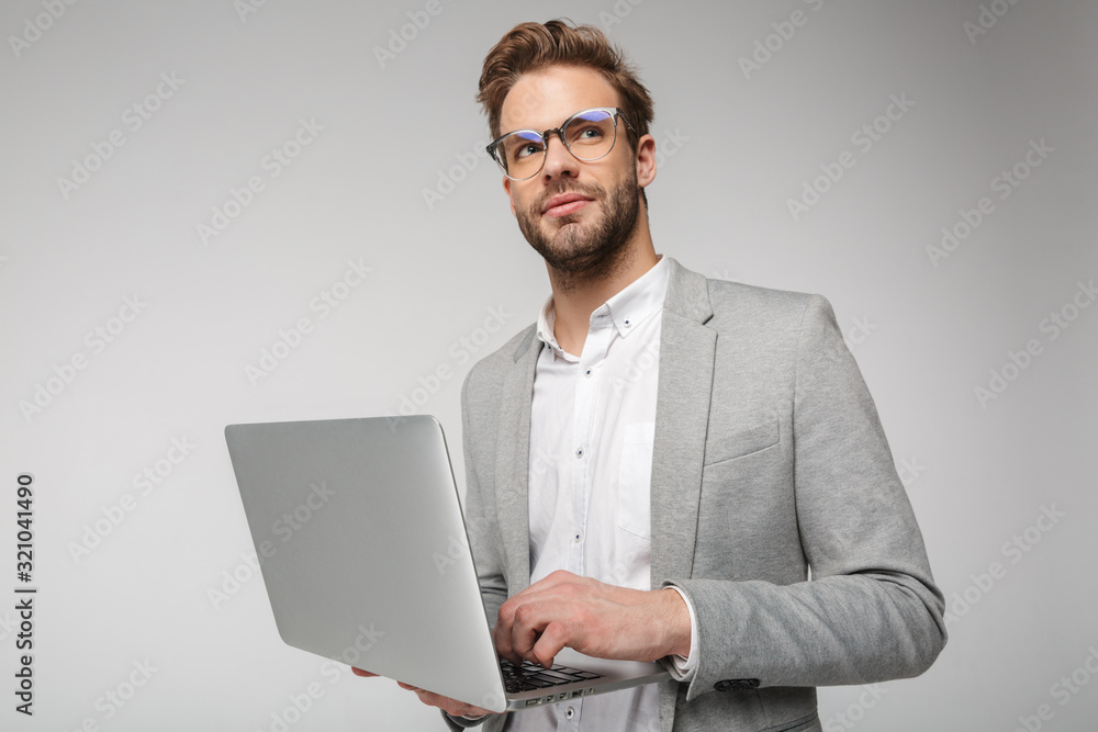 Portrait of pleased handsome man holding and using laptop Portrait of pleased handsome man holding and using laptop