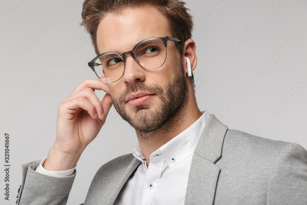 Portrait of serious handsome man in eyeglasses using earphones Portrait of serious handsome man in eyeglasses using earphones