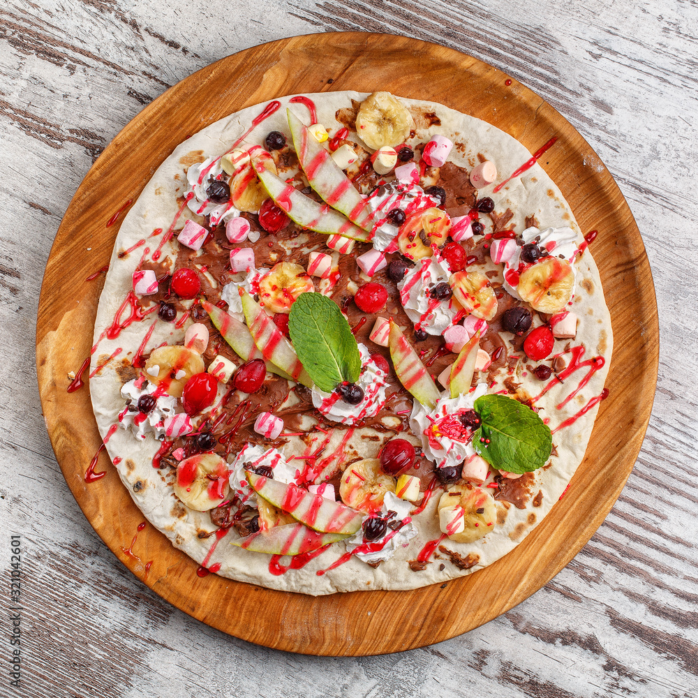 Baby sweet pizza with apples, bananas, chocolate and marshmallow on a wooden round tray. Children's menu Baby sweet pizza with apples, bananas, chocolate and marshmallow on a wooden round tray. Children's menu