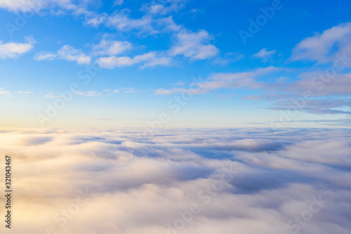 Aerial view White clouds in blue sky. Top view. View from drone. Aerial bird s eye view. Aerial top view cloudscape. Texture of clouds. View from above. Sunrise or sunset over clouds