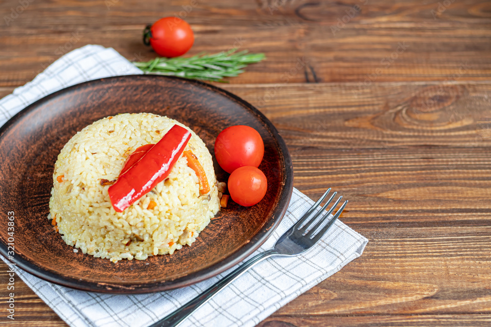 Rice with vegetables. Vegetarian dish. Mushrooms and carrots, onions, spices, hot chili peppers and garlic. Black pepper and zira. Cooking in olive oil. Healthy diet. On a wooden background. Rice with vegetables. Vegetarian dish. Mushrooms and carrots, onions, spices, hot chili peppers and garlic. Black pepper and zira. Cooking in olive oil. Healthy diet. On a wooden background.