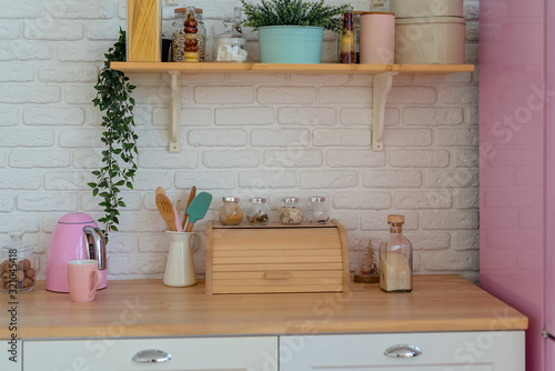 Modern kitchen with white wall  wooden countertop  breadbasket  shelves and pink fridge. Lifestyle kitchen decoration