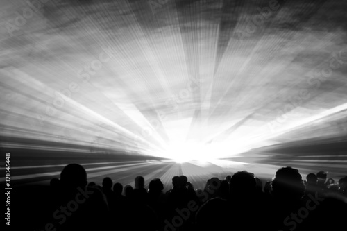 Grey laser show nightlife club stage with party people crowd. Luxury entertainment with audience silhouettes in nightclub event  festival or New Years Eve. Beams and rays shining colorful lights