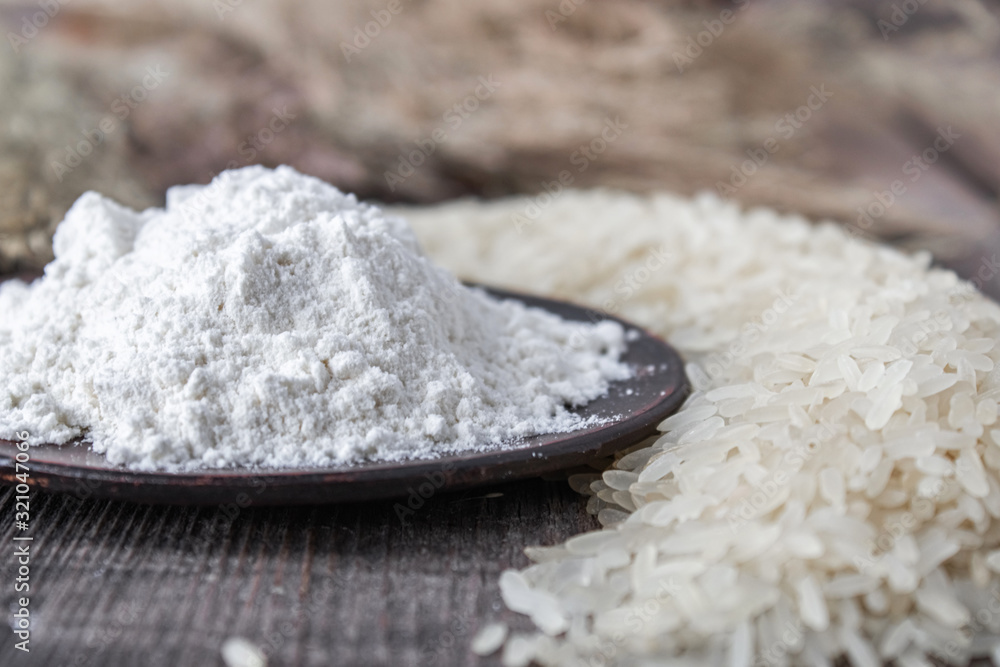 Rice flour in a bowl near the heap of white rice on old boards. Jasmine rice for cooking. Rice flour in a bowl near the heap of white rice on old boards. Jasmine rice for cooking.