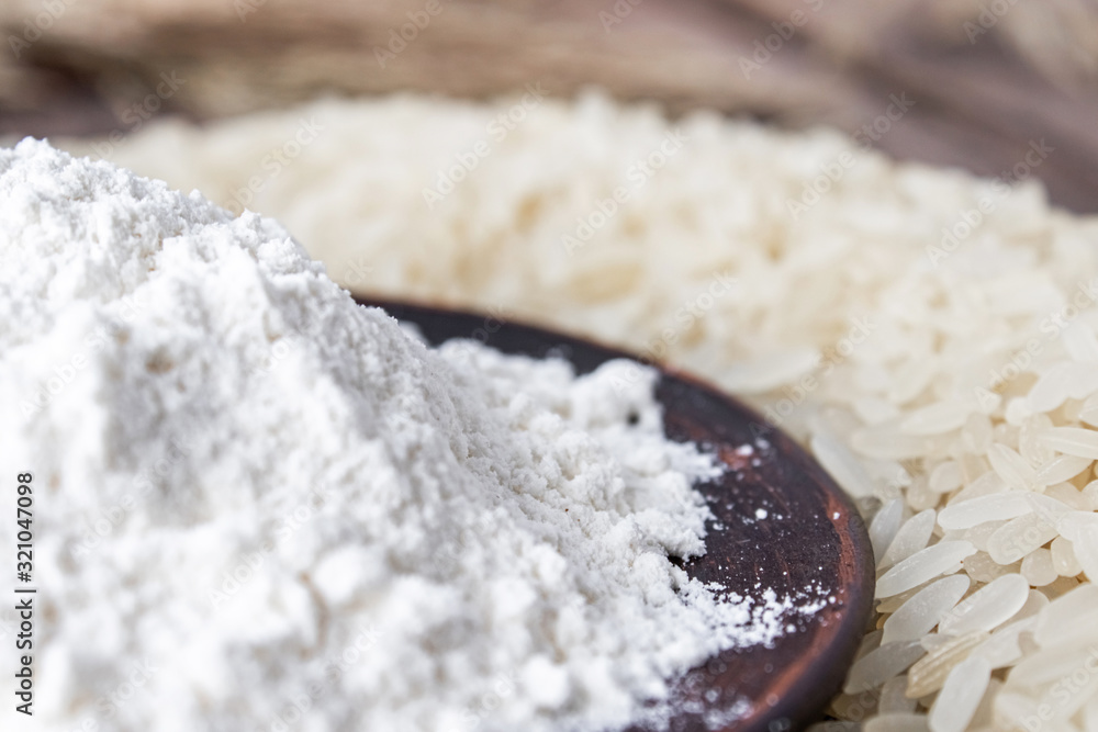 Rice flour in a bowl near the heap of white rice on old boards. Jasmine rice for cooking. Rice flour in a bowl near the heap of white rice on old boards. Jasmine rice for cooking.