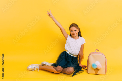 School girl in school clothes on a yellow background