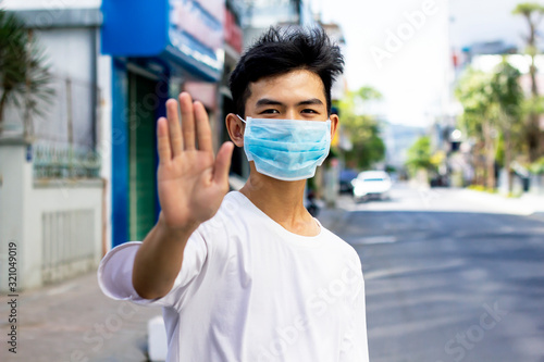 Asian guy, a man in a medical mask shows a gesture of sign hand or palm stop, emotion from the virus, colds, epidemics, flu.