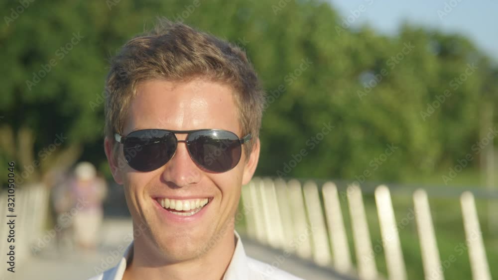 SLOW MOTION, CLOSE UP, PORTRAIT, DOF: Confident Caucasian businessman laughs while having fun at park on a sunny day. Cheerful male student smiles while enjoying a summer day in the idyllic outdoors. SLOW MOTION, CLOSE UP, PORTRAIT, DOF: Confident Caucasian businessman laughs while having fun at park on a sunny day. Cheerful male student smiles while enjoying a summer day in the idyllic outdoors.