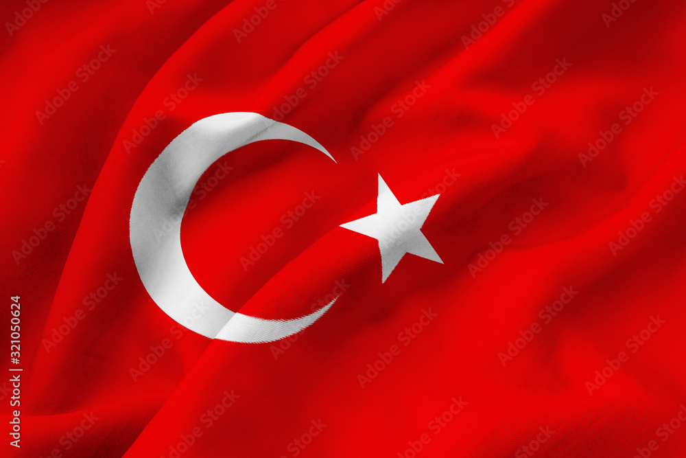 Turkish national flag waving in the wind. A closeup of the red silk standard of the Republic of Turkey with a white crescent and a white star. Turkey colors background.