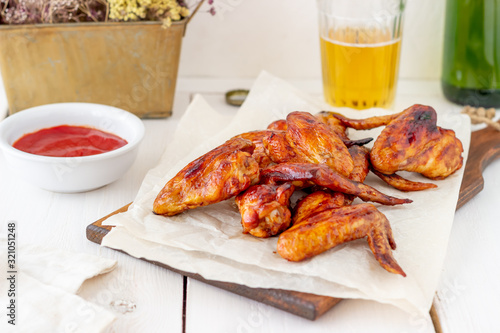 Grilled chicken wings with beer and red sauce on a wooden background. Snack to beer. Barbecue. Recipes.