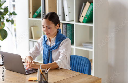 Image of young asian woman using laptop computer while working in office