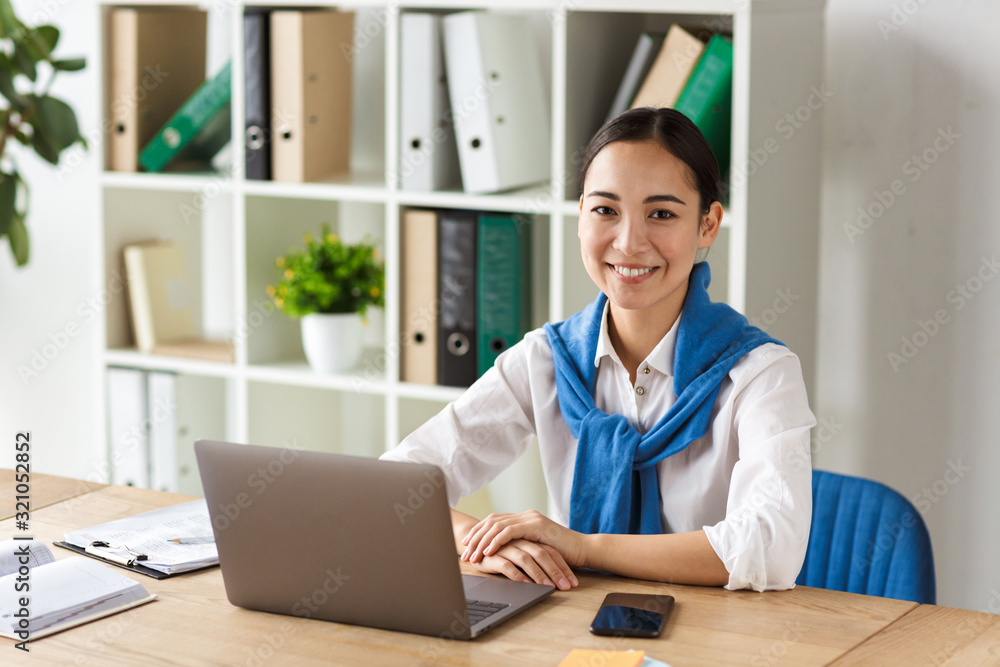 Image of young asian woman using laptop computer while working in office Image of young asian woman using laptop computer while working in office