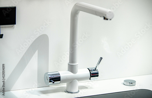 A steel water tap stands in the bathroom
