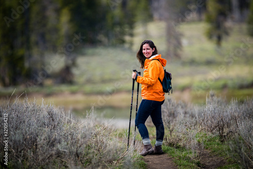 Self care exercise outdoors Young brunette beautiful attractive woman hiking in parka with walking sticks near forest in wilderness while camping