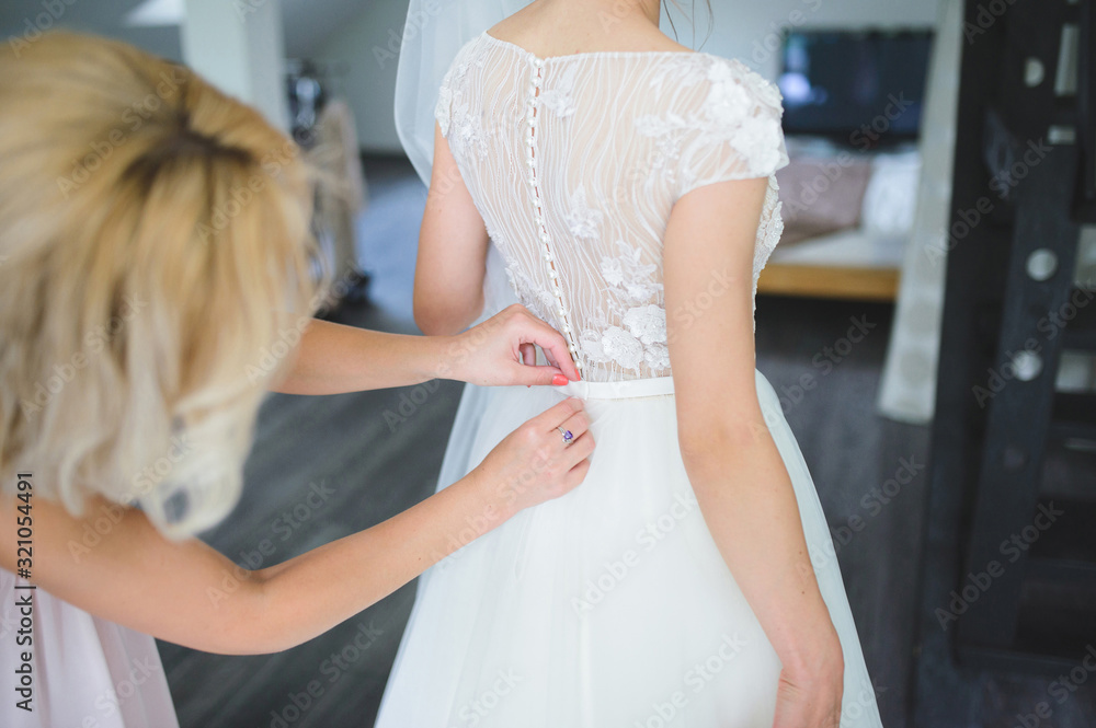 bridesmaid buttoning wedding dress