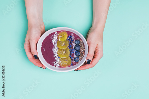 Woman's hands holding acai berry smoothie bowl