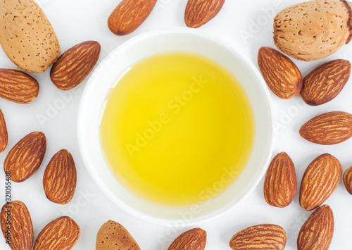 Small white bowl with almond oil. Top view, copy space. photo