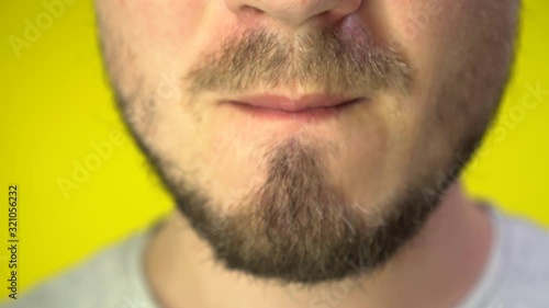 Close up of a bearded man's mouth chewing chewing gum. A man blowing out a bubble of bubble gum.