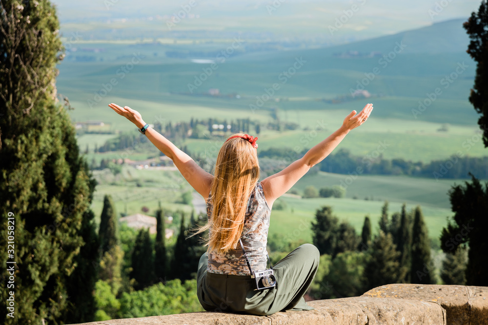 Young woman standing with her arms stretched enjoying the view of the Tuscany landscape Young woman standing with her arms stretched enjoying the view of the Tuscany landscape