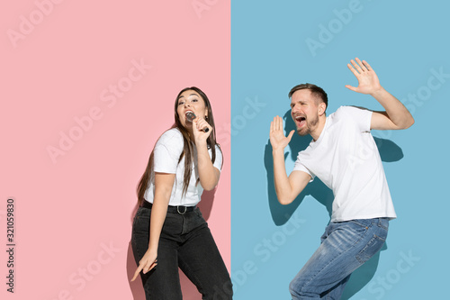 Spring season. Dancing, singing, having fun. Young, happy man and woman in casual on pink, blue bicolored background. Concept of human emotions, facial expession, relations, ad. Beautiful couple.