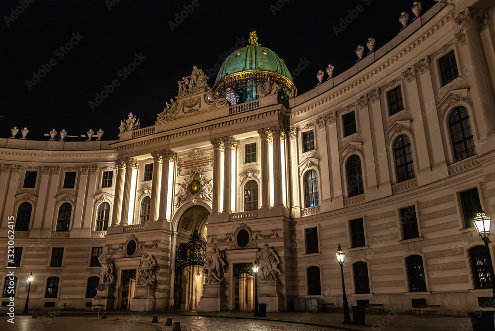 Fototapeta premium Vienna, Austria. Hofburg Palace main entrance seen from Michaelerplatz at night, wide-angle view at dusk, Habsburg Empire landmark in Vienna