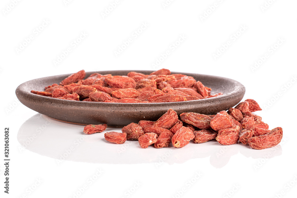 Lot of whole dried red goji berries with brown ceramic coaster isolated on white background Lot of whole dried red goji berries with brown ceramic coaster isolated on white background