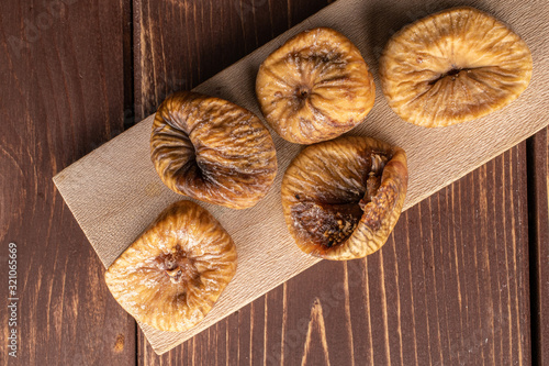 Group of five whole dried fig on wooden cutting board flatlay on brown wood